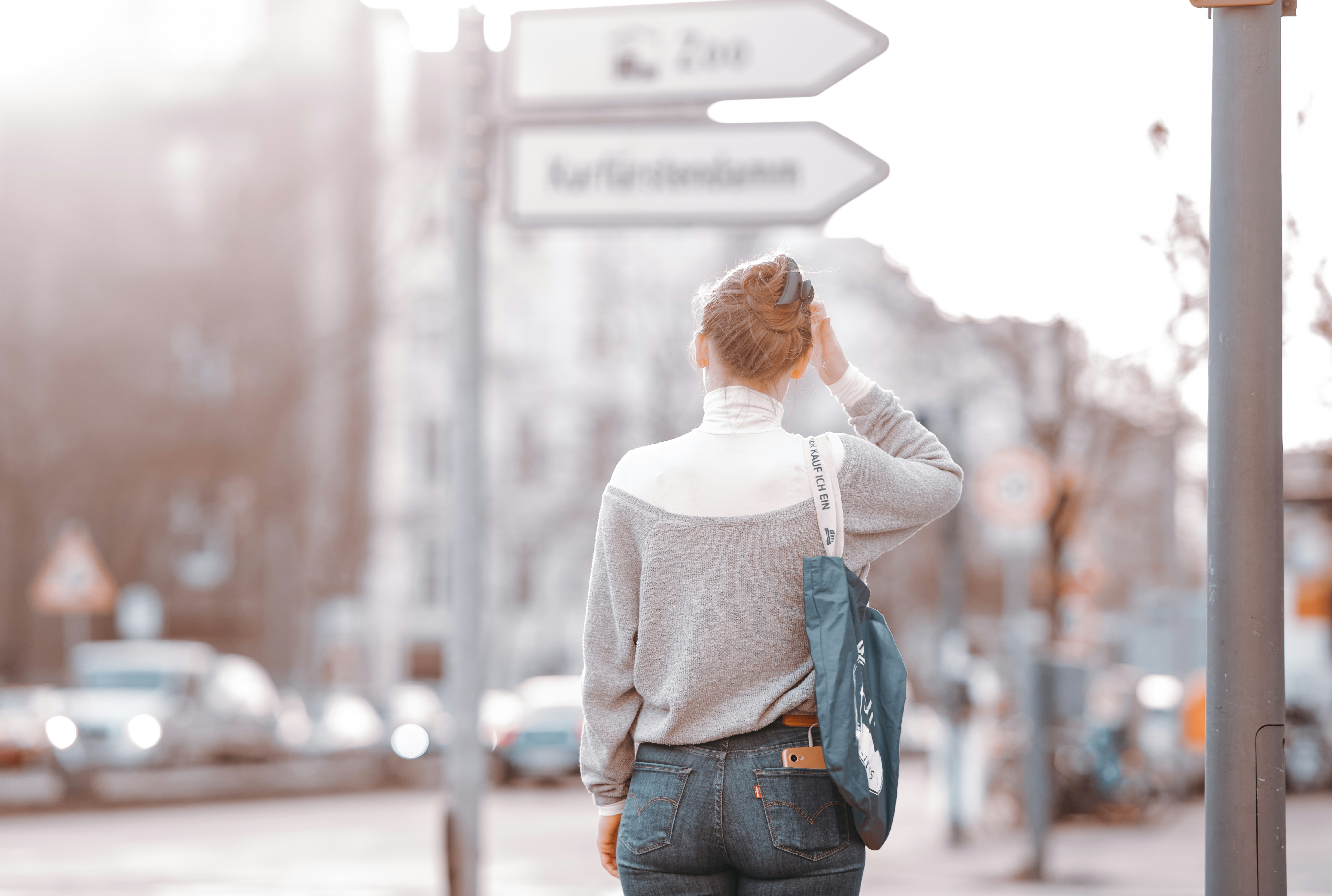 Jeune femme de dos, hésitante devant un panneau de signalisation
